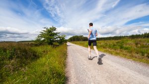 Man jogging on a road through a field