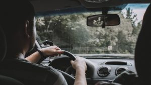 An interior photo of a person driving a car in a wooded area