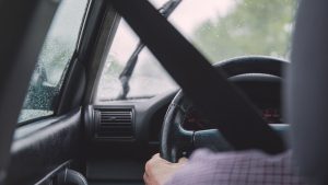 Man wearing seatbelt and driving cautiously in the rain