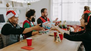 A group of people gathering around a table and exchanging gifts