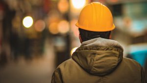 A worker wearing a hard hat with their back turned to the camera