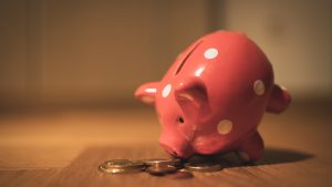 A polka-dotted piggy bank with coins underneath it