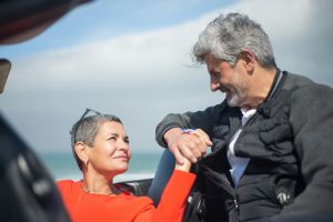 couple in a car holding hands with ocean in the background