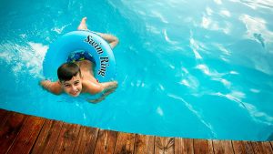 Child in a swim ring splashing in a pool