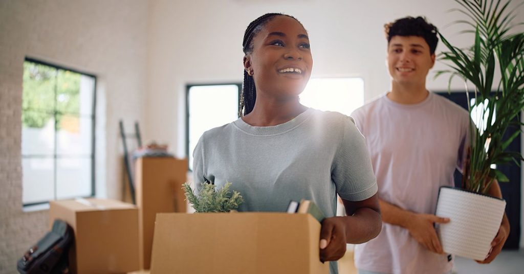 Couple reviewing a moving checklist and insurance documents while preparing to move to a new state