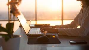 Woman typing on a computer at sunset