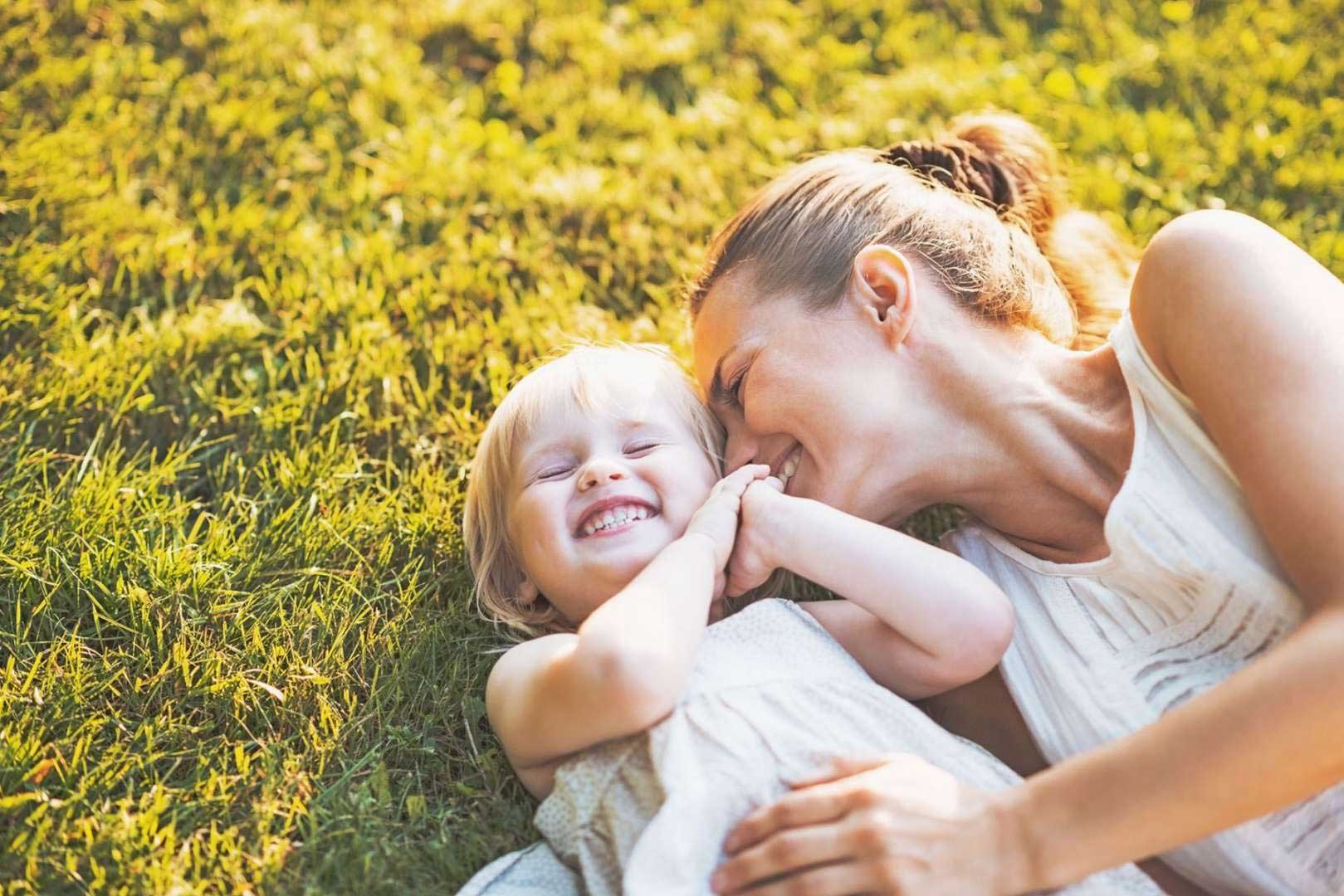 Woman laying in grass with daughter