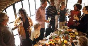 People standing around a meal drinking wine