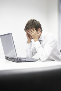 Man on laptop with head in hands