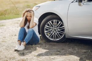 Woman sitting near car with her head in her hands