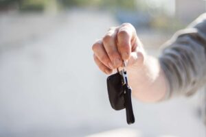 Person handing over car keys for article about what your auto insurance covers when someone borrows your car
